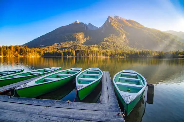 Photo of Amazing autumn scenery on Hintersee lake with boats moored on wooden pier, Bavaria, Germany