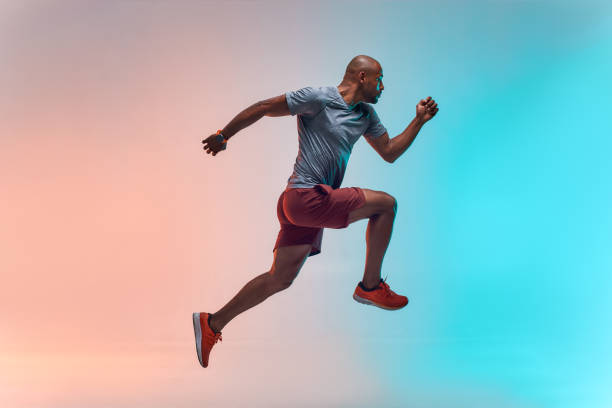 nouveau champion. pleine longueur de jeune homme africain dans le saut de vêtements de sports sur le fond coloré - sports and fitness photos et images de collection