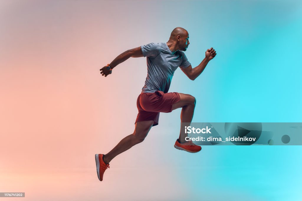 New champion. Full length of young african man in sports clothing jumping against colorful background New champion. Full length of young african man in sports clothing jumping against colorful background. Sport concept. Motivation. Healthy lifestyle Exercising Stock Photo