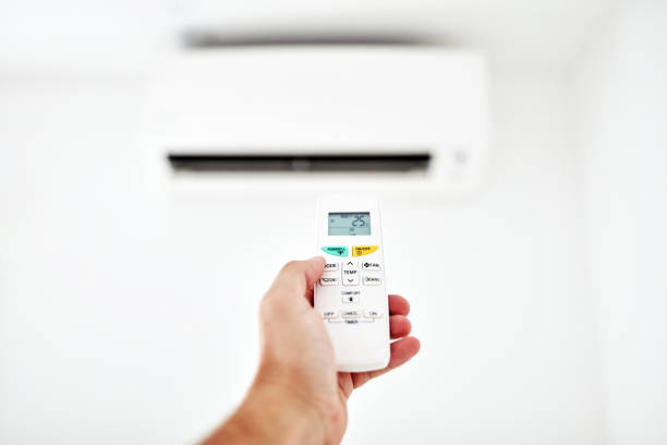 istock Modern air conditioner unit with a hand holding a remote. 1176741648