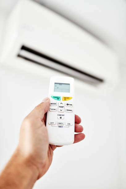 istock Modern air conditioner unit with a hand holding a remote. 1176741672