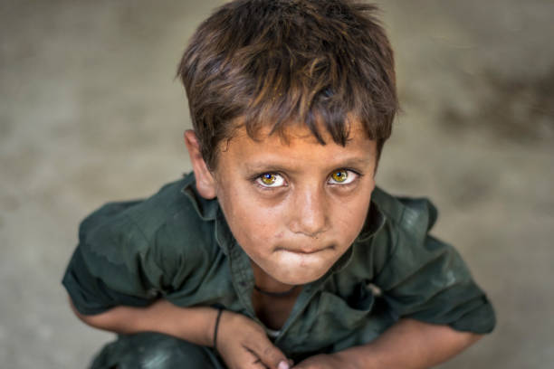 closeup of a poor staring hungry orphan boy in a refugee camp with sad expression on his face and his face and clothes are dirty and his eyes are full of pain closeup of a poor staring hungry orphan boy in a refugee camp with sad expression on his face and his face and clothes are dirty and his eyes are full of pain orphan stock pictures, royalty-free photos & images