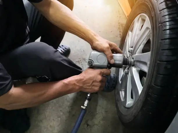 Photo of Removing car mechanic to repair the leaky tire car wheels.Mechanic changing a car tire on a vehicle a hoist using an electric drill to loosen the bolts .concept of service or replacement.