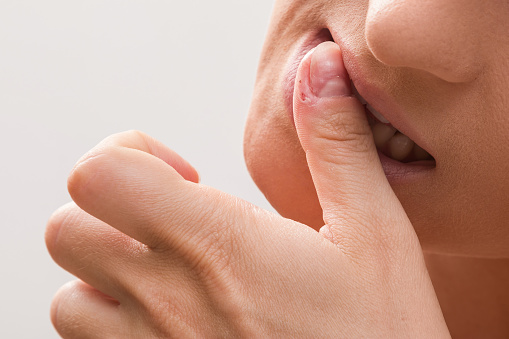 Close up of a female mouth biting her fingers