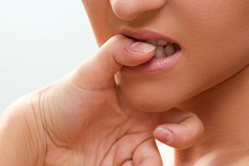 Close up of a female mouth biting her fingers