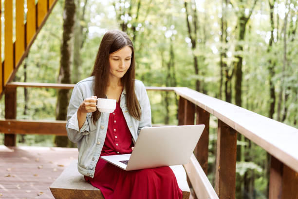 istock woman with laptop and coffee outside 1176748195