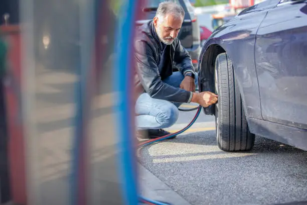 Mature Man Inflating Car Tires.