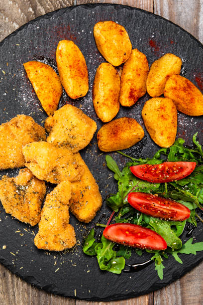 istock Fried chicken nuggets with baked potatoes and vegetables 1176751686
