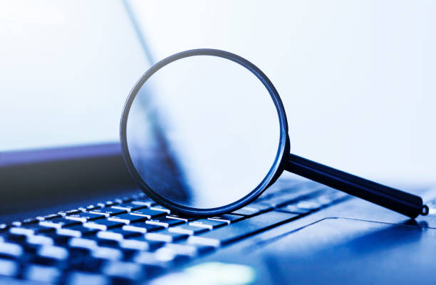 Laptop computer with magnifying glass, concept of search
