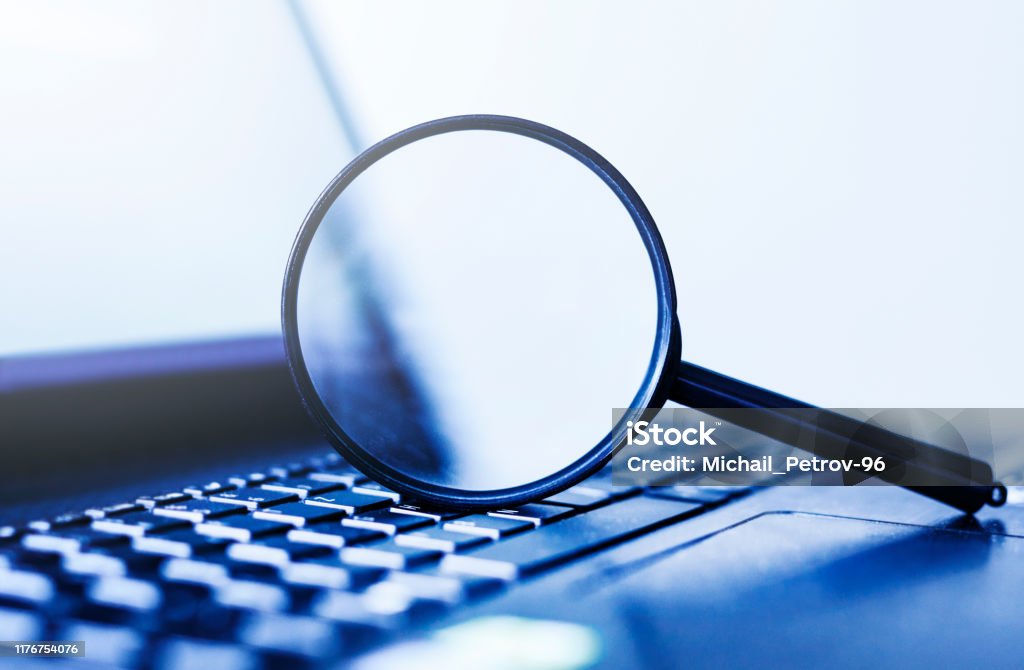 Laptop computer with magnifying glass, concept of search Surveillance Stock Photo