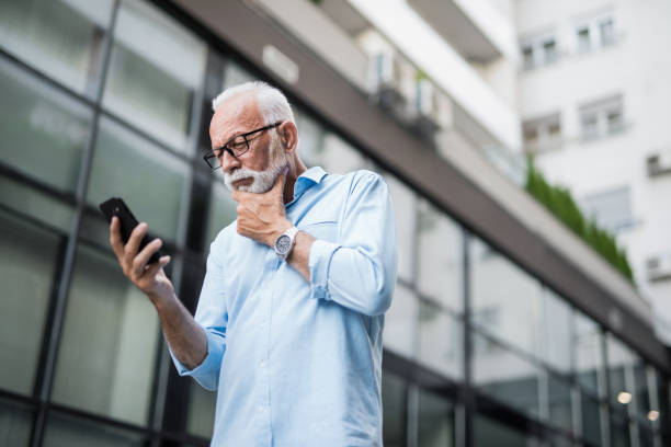 istock Serious elegant senior man looking at phone and thinking. 1176754343