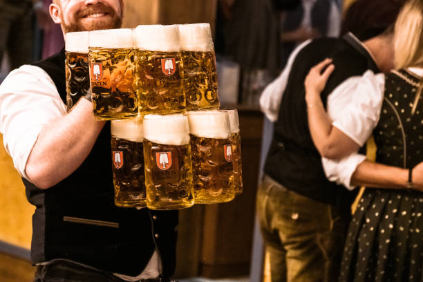 waiter carrying a lot of beers in beer tent at Octoberfest Munich, Germany - September 21, 2019: waiter carrying a lot of beer glasses in beer tent at Octoberfest in Munich oktoberfest beer stock pictures, royalty-free photos & images