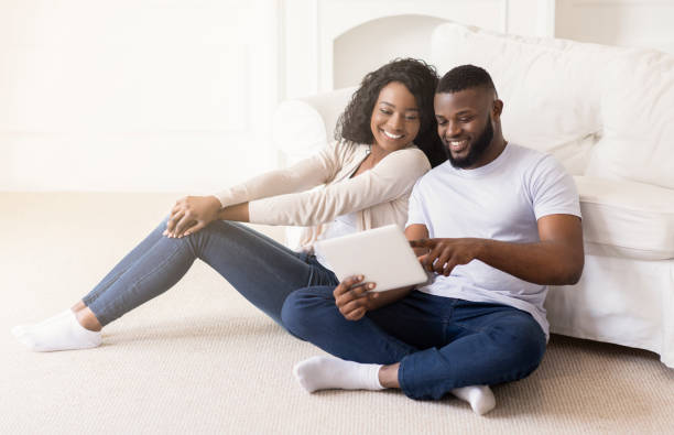 istock Cheerful couple using digital tablet together while sitting at home 1176756126