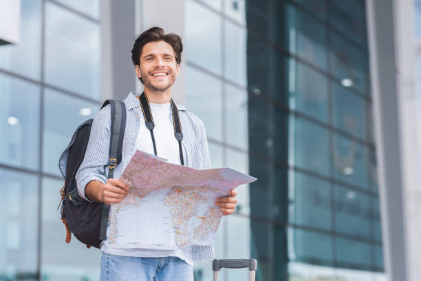 turista milenario que busca ruta en el mapa en el aeropuerto - tourist map men holding fotografías e imágenes de stock