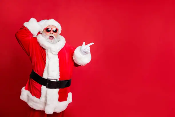 Portrait of his he nice attractive cheerful cheery glad stunned bearded Santa showing ad advert copy space present gift surprise, isolated over bright vivid shine red background