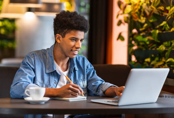 Young teen blogger making notes for new publication at cafe African teen male blogger writing ideas for publication, making notes at cafe, copy space first job photos stock pictures, royalty-free photos & images