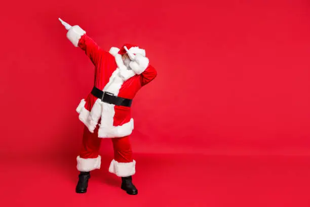 Photo of Full length body size view of his he carefree fat overweight plump gray-haired, bearded man St Saint Nicholas having fun christmas time occasion isolated over bright vivid shine red background