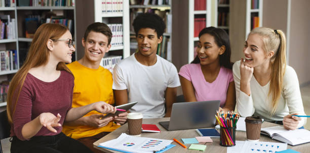 międzynarodowa grupa studentów siedzących w bibliotece, odrabiająca pracę domową - book working college student classroom zdjęcia i obrazy z banku zdjęć