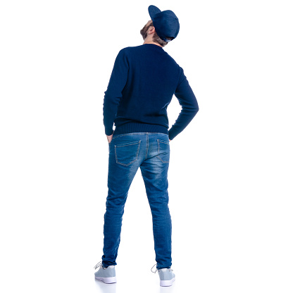 Man in jeans shorts, cap, casual clothing standing looking up on white background isolation, rear view