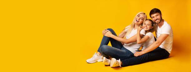 Family Of Three Relaxing Together Sitting On Floor, Studio, Panorama