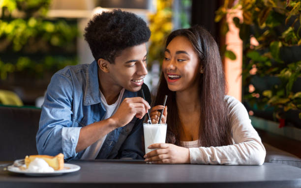 cute couple of teenagers enjoying milkshake at cafeteria - men elegance cocktail cool imagens e fotografias de stock