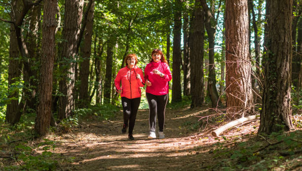 istock Two middle aged women running through a forest 1176760950