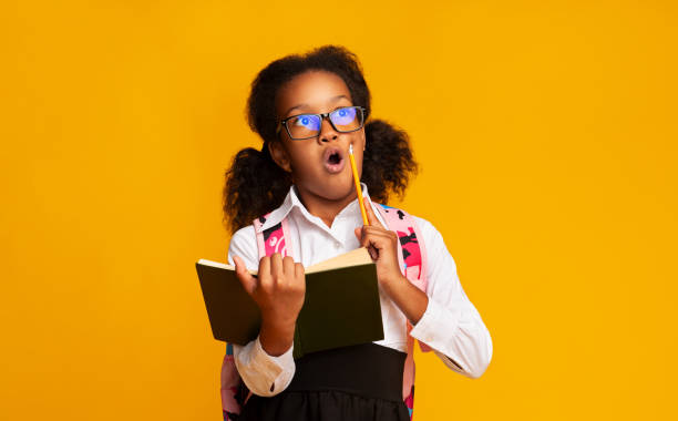 istock Amazed Afro Schoolgirl Doing Homework Holding Book And Pencil, Studio 1176760961