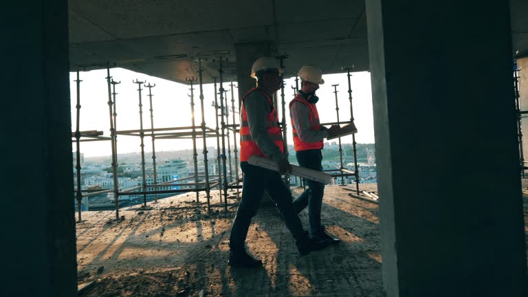 Construction workers are walking along the building in progress