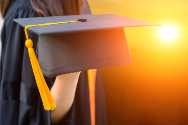 istock Graduates holding black hats during sunset 1176763760