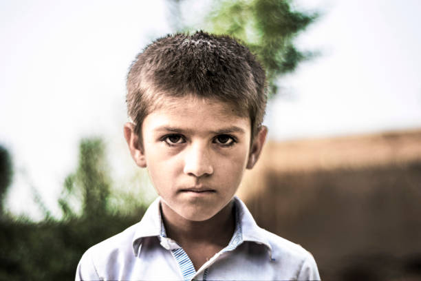 istock closeup of a poor staring hungry orphan boy in a refugee camp with sad expression on his face and his face and clothes are dirty and his eyes are full of pain 1176766176