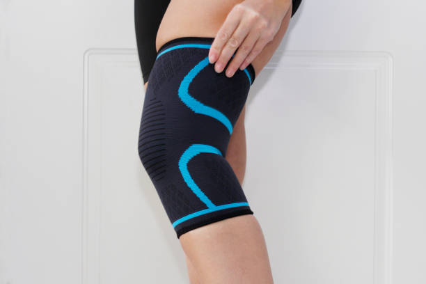 Elastic anatomical knee pad after knee injury. Elastic bandage on the knee. Elastic anatomical knee pad after knee injury. Sprain of the knee. kneepad stock pictures, royalty-free photos & images