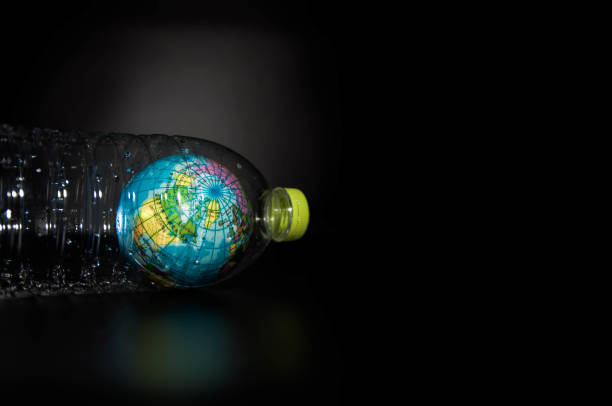 istock A globe in a plastic bottle on black background, which is concept of global environment from plastic. 1176768426