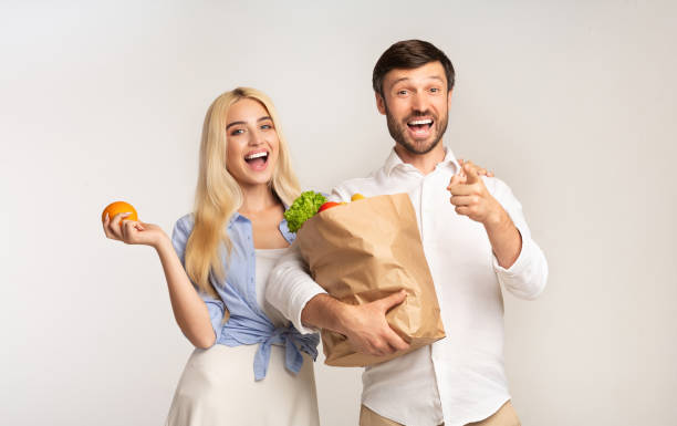 istock Excited Couple Pointing Finger At Camera Holding Grocery Bag, Studio 1176772661