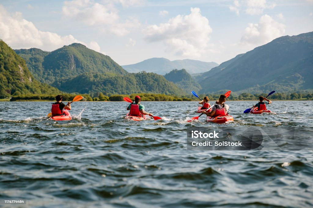Friends Learning To Kayak Friends learning to kayak on Derwent Water in The Lakes District in Cumbria Kayaking Stock Photo