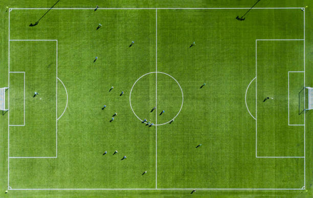 Green football pitch Aerial View Aerial view of Green football pitch with unrecognizable little player silhouettes; outdoors. soccer field stock pictures, royalty-free photos & images
