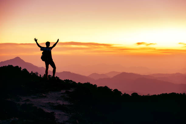 istock Hiker's silhouette stands on mountain top against sunset 1176780081