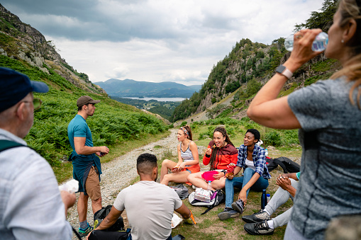 A group of young males and females resting and having refreshments after a long trek in The Lake district in Cumbria