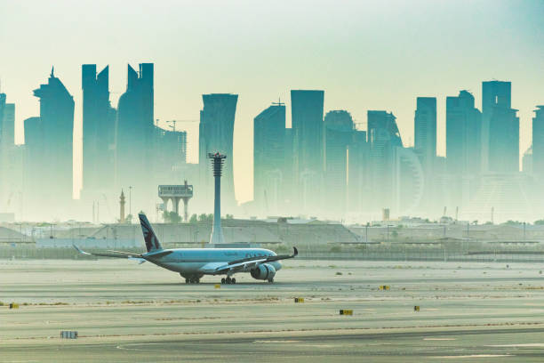 vuelo de qatar airways que se prepara para salir del aeropuerto internacional de hamad con el horizonte de la ciudad - depart fotografías e imágenes de stock
