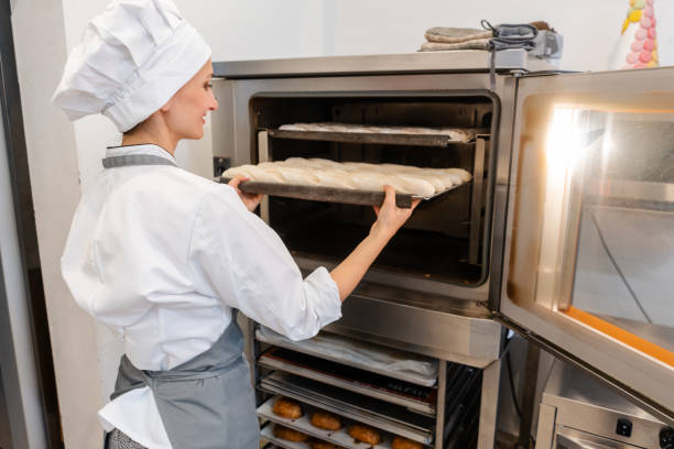 istock Baker woman putting baking sheet in the oven 1176781709