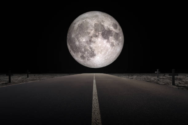 istock Halloween Concept : Empty road leading to full moon flanked with tomb in dark night. 1176782994