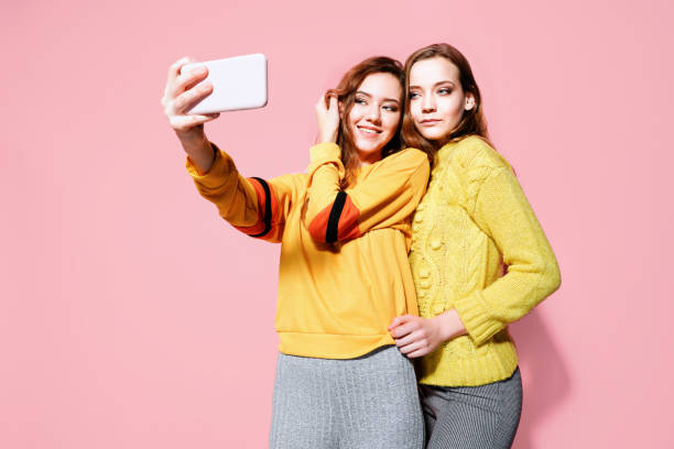 istock Two cheerful young women talking selfie over pink background 1176783895