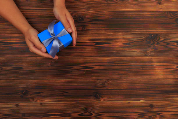 istock gift in female hands on a wooden background top view. 1176784081