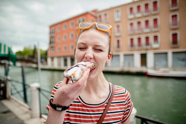 Trying a Cannoli Close up of a female biting into a cannoli while on vacation in Italy with her eyes closed and sunglasses on her head. cannoli photos stock pictures, royalty-free photos & images