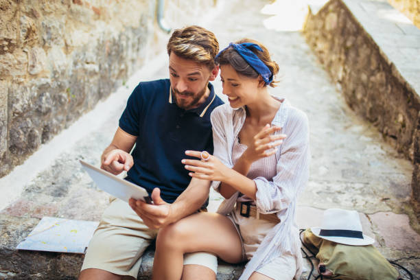 istock Romantic tourist couple sitting on stairs using digital tablet. 1176784223