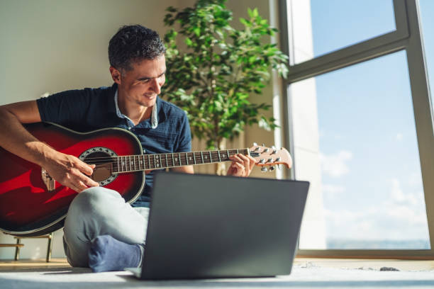Young Man Practicing Acoustic Guitar At Home