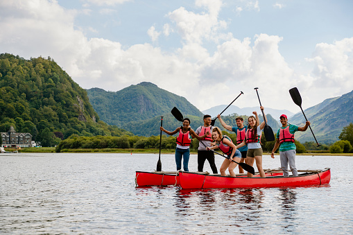 A group of friends standing in kayaks and cheering on Derwent Water in The Lakes District in Cumbria