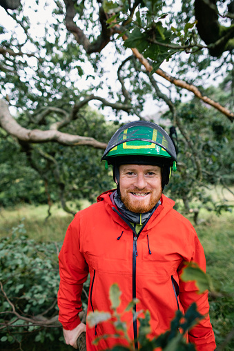 Man with beard smiling towards camera wearing safety gear in woods
