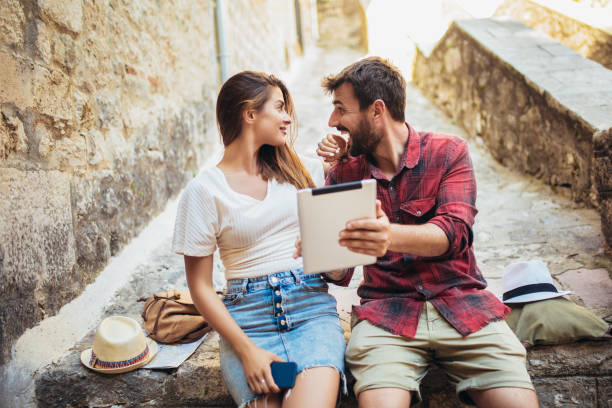 istock Romantic tourist couple sitting on stairs using digital tablet. 1176787858