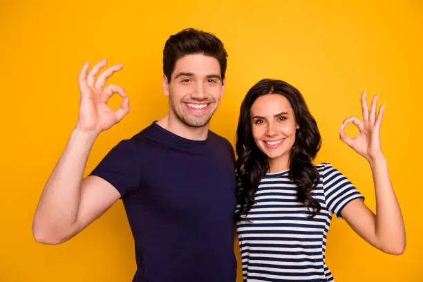 Close-up portrait of his he her she nice attractive lovely cheerful cheery, glad content people showing ok-sign ad advert solution isolated over bright vivid shine yellow background