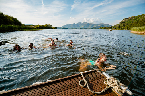A group of young multi ethnic friends swimming in a lake in Derwent Water in Cumbria